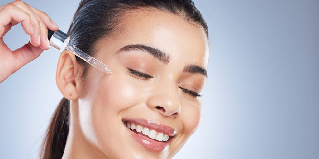 Woman applying facial serum to her skin with fingertips