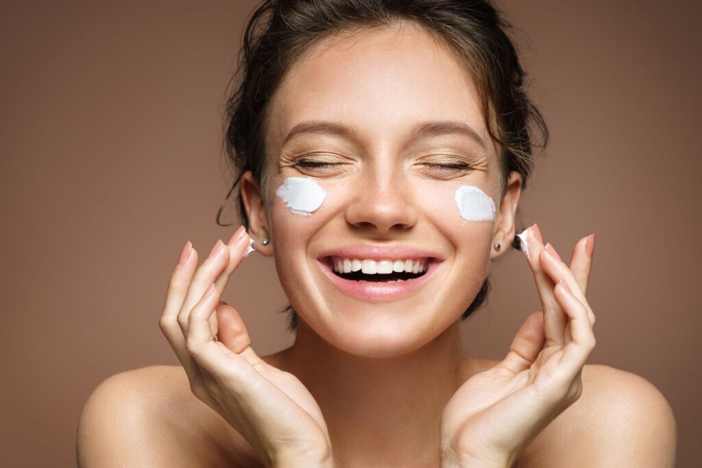 "Close-up of a woman applying light cream to her face to use moisturizer in summer for healthy, hydrated skin."